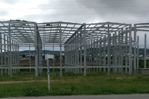 Estrutura de galpão montada em terreno aberto, com pilares e terças à vista