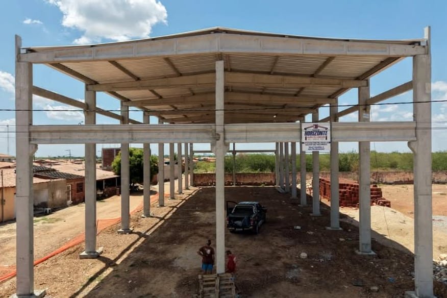 Estrutura ampla já coberta, com pessoas e veículo dando noção da escala